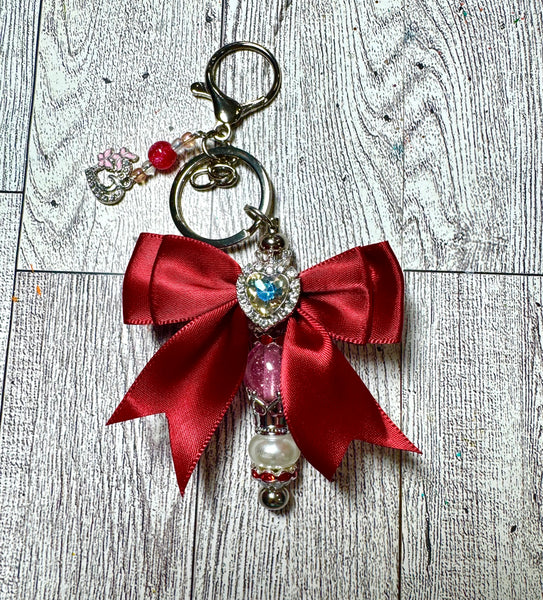 Keychain with red bow and decorative beads on a wooden surface