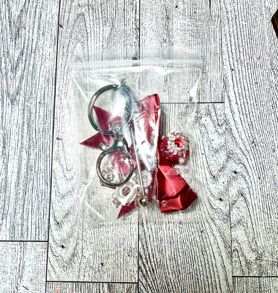 Keychain with red ribbon and decorative elements in clear packaging on a wooden surface